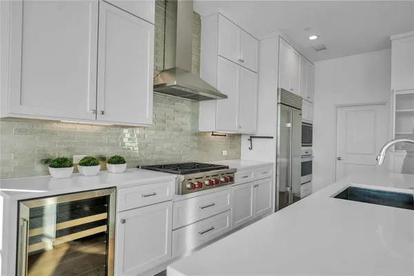 a large kitchen with stainless steel appliances a large counter top a sink a refrigerator and a window