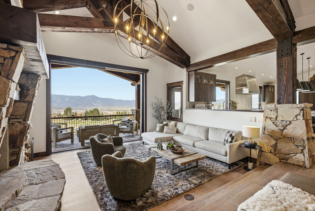 7885 North Rabbitbrush Court, Unit 13 Park City, UT 84098 - Photo 7 of 88 Open-concept living area featuring a stone fireplace, vaulted ceiling with exposed wood beams, and a large sliding glass door opening to an outdoor balcony