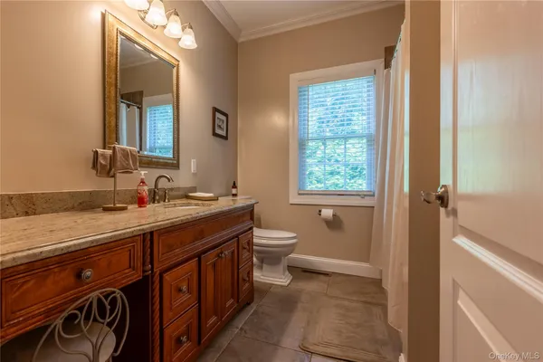 a spacious bathroom with a granite countertop sink toilet a mirror and a tub