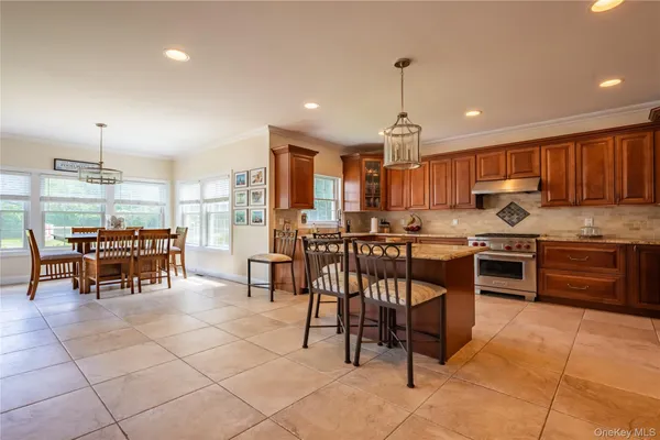 a kitchen with stainless steel appliances granite countertop a stove top oven a sink a table and chairs