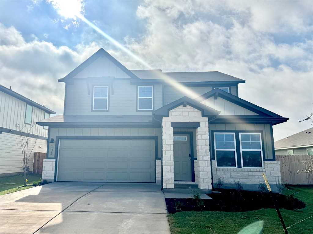 Craftsman inspired home with stone siding, driveway, board and batten siding, and a garage