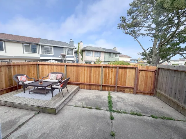 a view of a patio with couches chairs and wooden fence