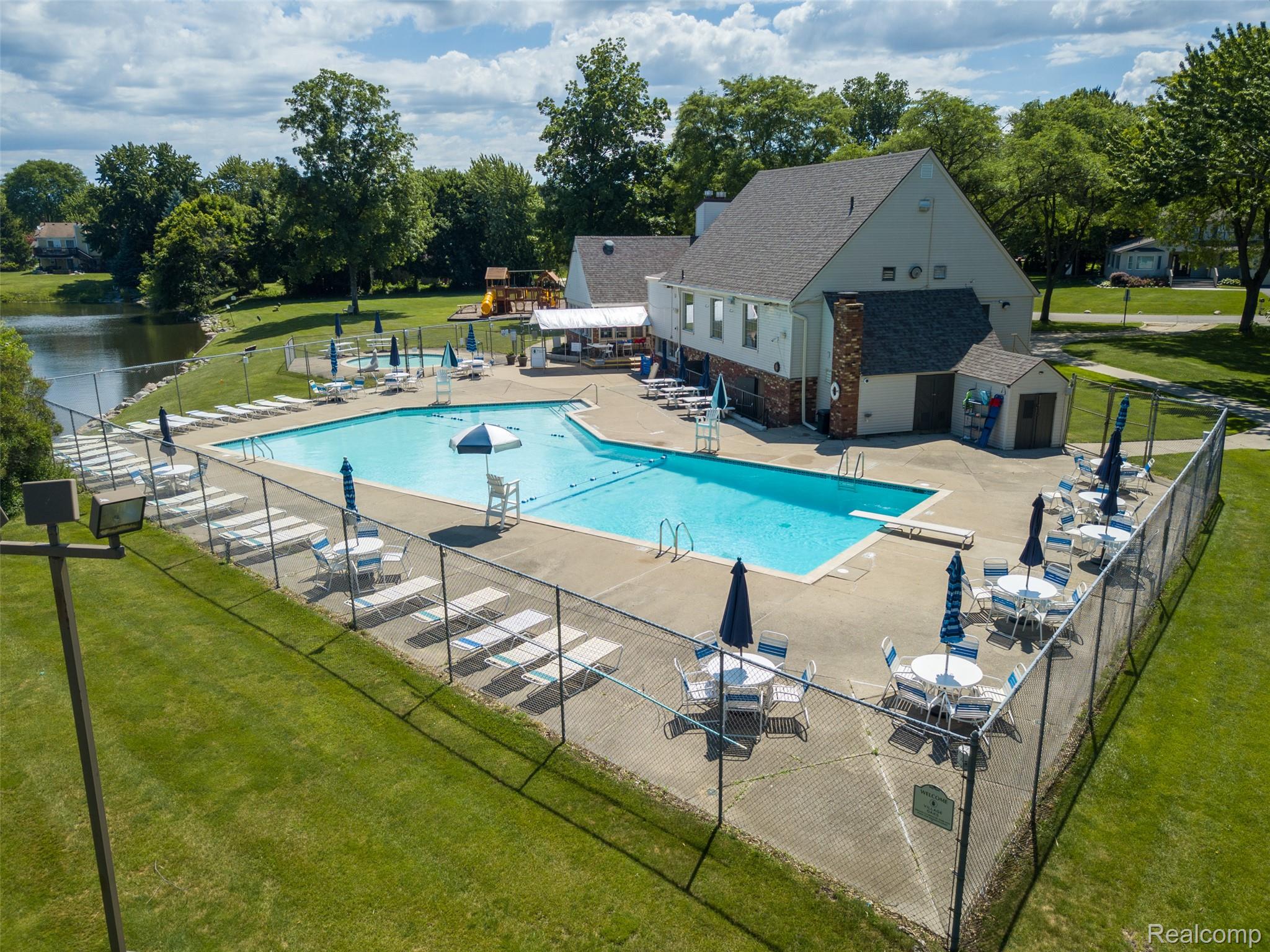 22533 Winfield Road Novi, MI 48375 - Photo 35 of 43 Community pool area featuring a large swimming pool, surrounding concrete patio, and perimeter chain-link fencing