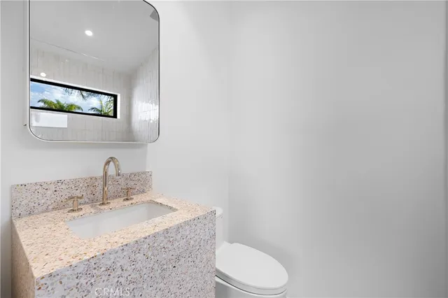 a bathroom with a granite countertop sink mirror vanity and toilet