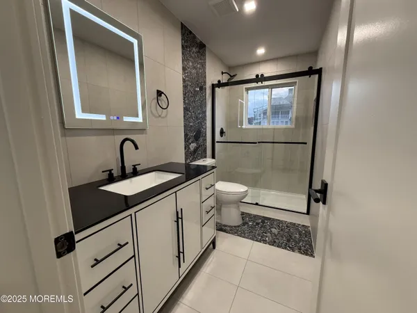 a bathroom with a sink a toilet a mirror and shower