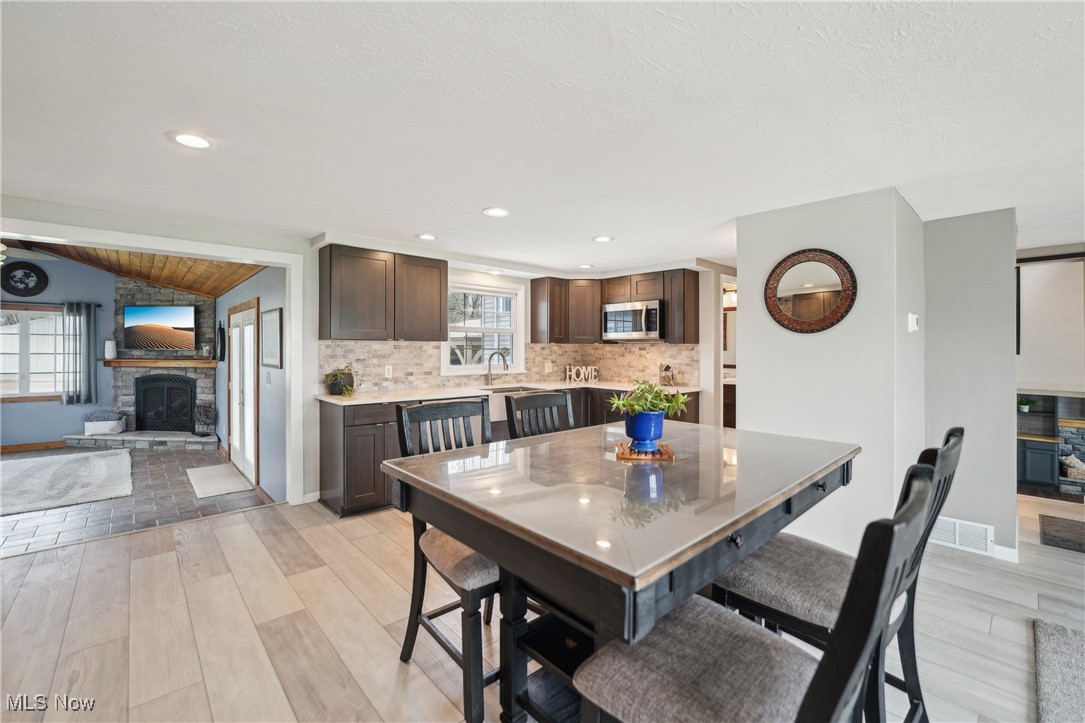 15415 Mason Road Vermilion, OH 44089 - Photo 14 of 50 Dining space featuring vaulted ceiling, a fireplace, baseboards, light wood-style floors, and recessed lighting