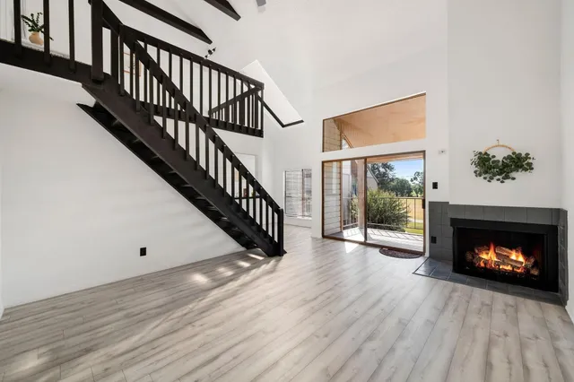 a view of an empty room with wooden floor a fireplace and a window
