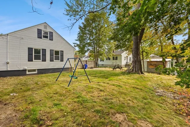 a view of a house with a yard and large tree