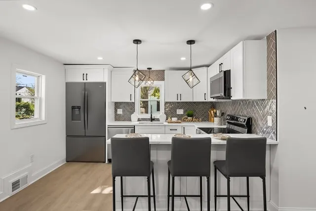 a kitchen with stainless steel appliances granite countertop a sink a stove a refrigerator and island with wooden floor