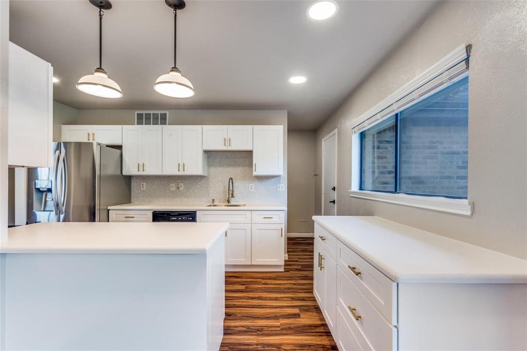 7904 Simpkins Place Plano, TX 75025 - Photo 10 of 24 a large kitchen with stainless steel appliances kitchen island a large counter space a sink and a chandelier
