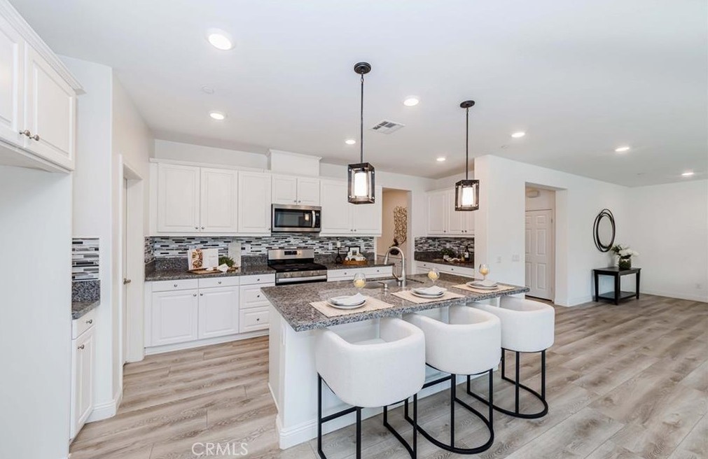 20886 Mountain Gate Drive Riverside, CA 92507 - Photo 13 of 27 a kitchen with stainless steel appliances kitchen island granite countertop a dining table chairs refrigerator and microwave