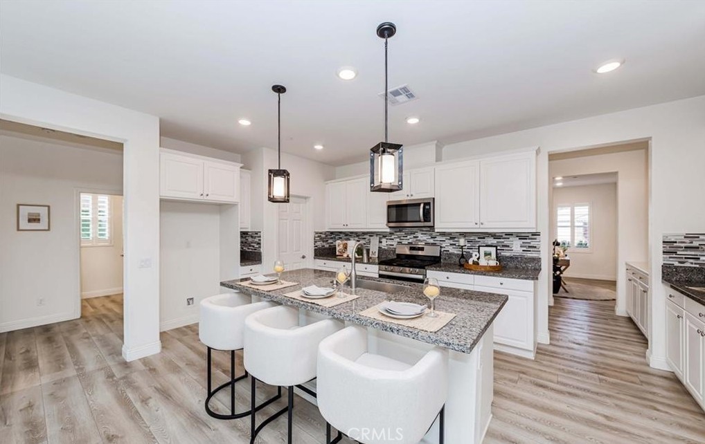 20886 Mountain Gate Drive Riverside, CA 92507 - Photo 16 of 27 a kitchen with stainless steel appliances kitchen island granite countertop a stove a sink a refrigerator and chairs with wooden floor
