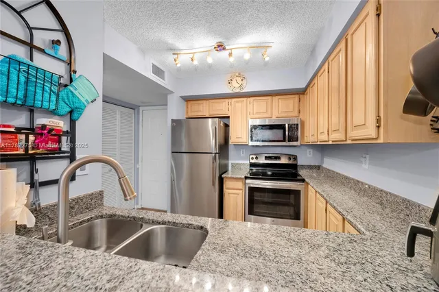 a kitchen with stainless steel appliances granite countertop a sink a stove and refrigerator