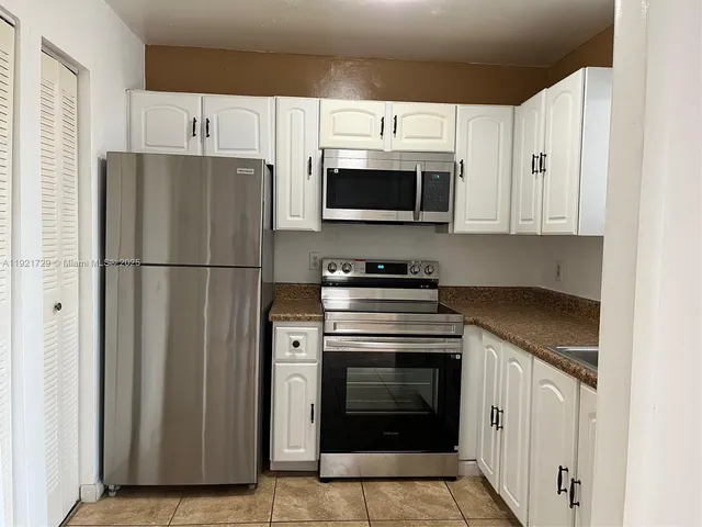 a kitchen with cabinets stainless steel appliances and a window