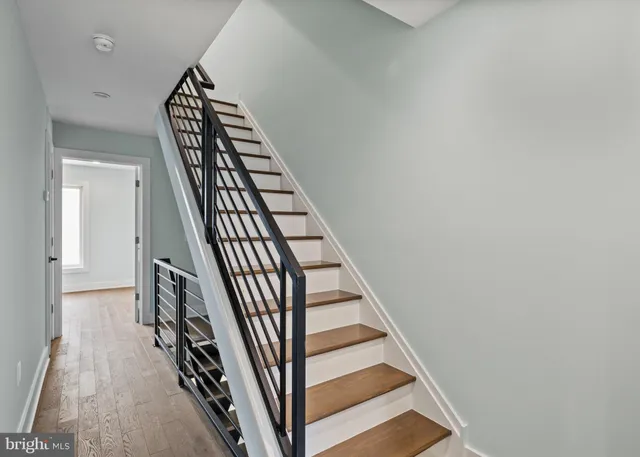 a view of staircase with wooden floor and white walls