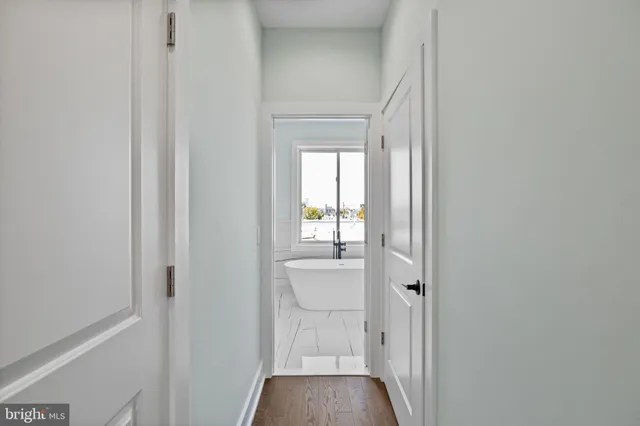 a view of a hallway with wooden floor and a bathroom
