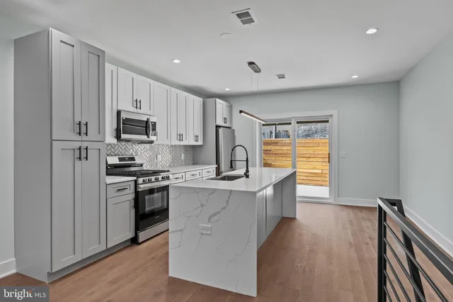 a kitchen with kitchen island a sink stainless steel appliances and cabinets