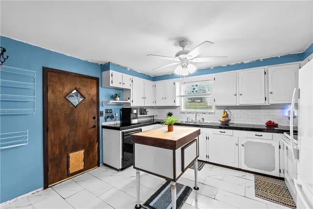 a kitchen with stainless steel appliances a sink a stove a refrigerator and white cabinets