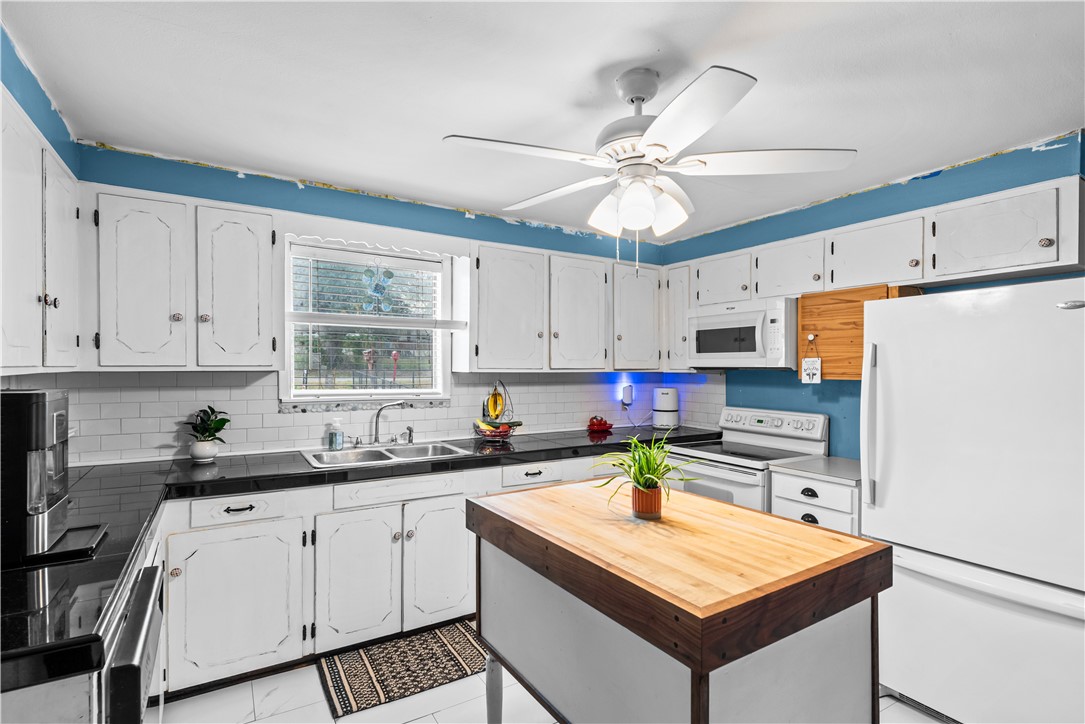 9505 County Road 505 Mathis, TX 78368 - Photo 9 of 19 a kitchen with stainless steel appliances a sink a stove a refrigerator and white cabinets