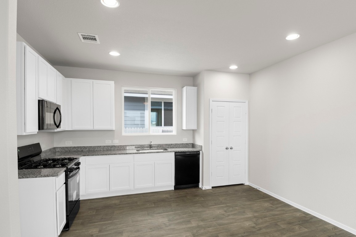 2963 Winding Creek Road Kyle, TX 78640 - Photo 16 of 28 a kitchen with stainless steel appliances granite countertop a stove a sink and a refrigerator