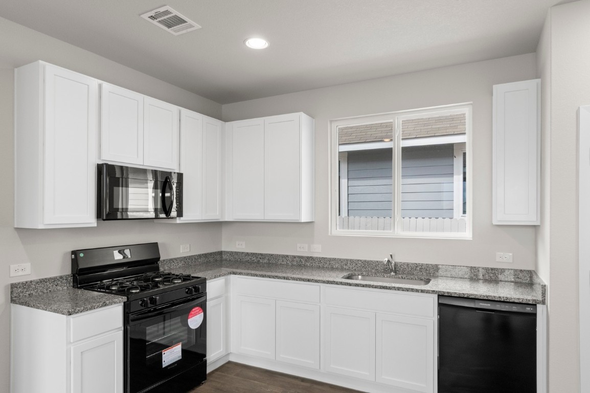 2963 Winding Creek Road Kyle, TX 78640 - Photo 8 of 28 a kitchen with stainless steel appliances granite countertop a sink stove and cabinets