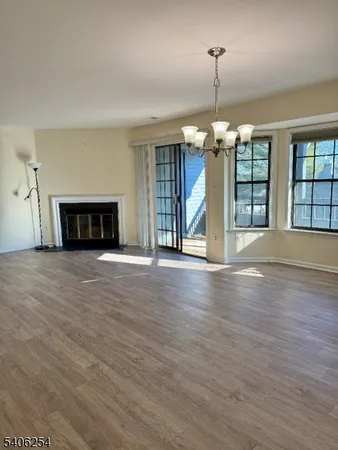 an empty room with wooden floor fireplace and windows