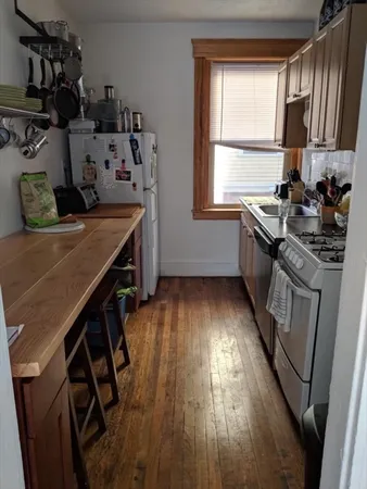 a kitchen with stainless steel appliances granite countertop a stove a sink dishwasher and a refrigerator with wooden floor