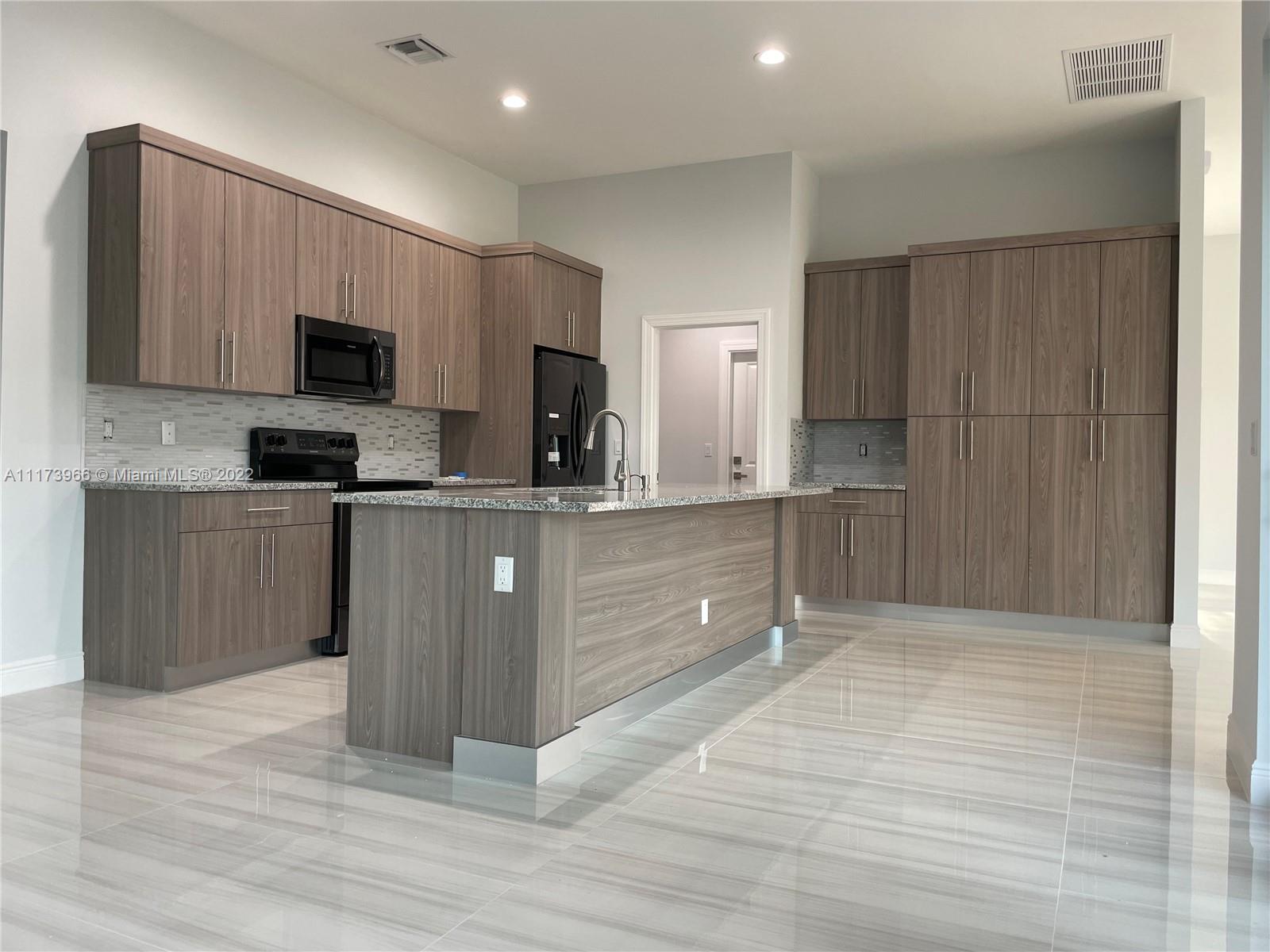 2072 Southwest Akorot Road Port St. Lucie, FL 34953 - Photo 3 of 14 a large kitchen with stainless steel appliances granite countertop a stove a sink and a refrigerator