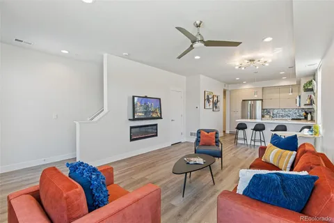 a living room with furniture kitchen view and a wooden floor