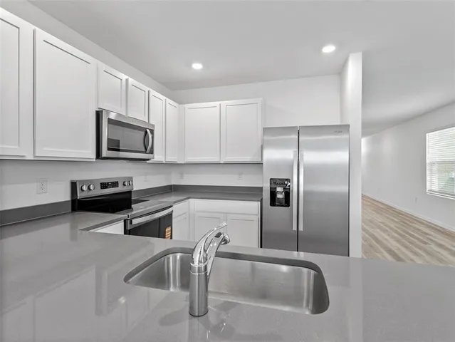 a kitchen with stainless steel appliances granite countertop a sink a microwave and a refrigerator