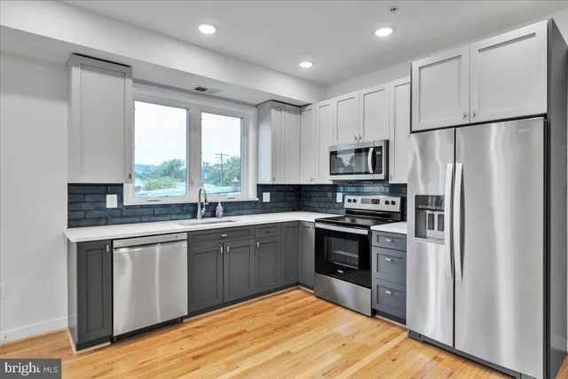 a kitchen with granite countertop stainless steel appliances a sink cabinets and a window