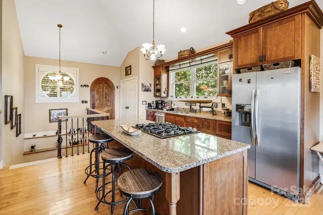 a kitchen with stainless steel appliances granite countertop a kitchen island a table and chairs in it