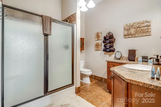 a bathroom with a granite countertop sink a toilet and a shower