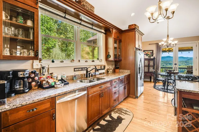 a large kitchen with stainless steel appliances a large counter top a stove and a wooden floors