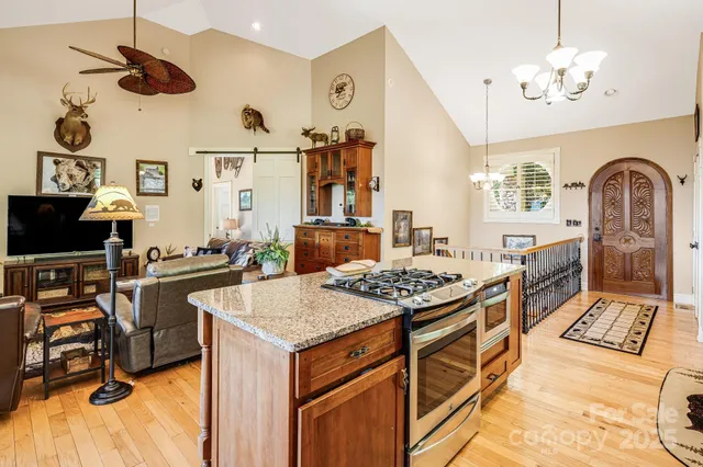 a kitchen with stainless steel appliances granite countertop a stove and a view of living room