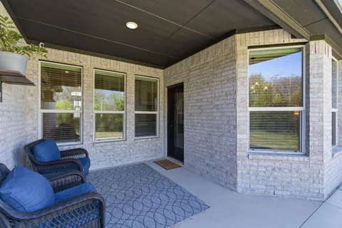 a view of backyard with seating space and trees in the background