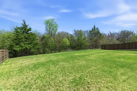 a view of a house with a yard and large tree