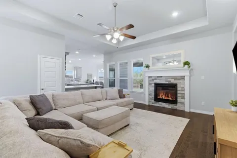 a living room with furniture a fireplace and a ceiling fan