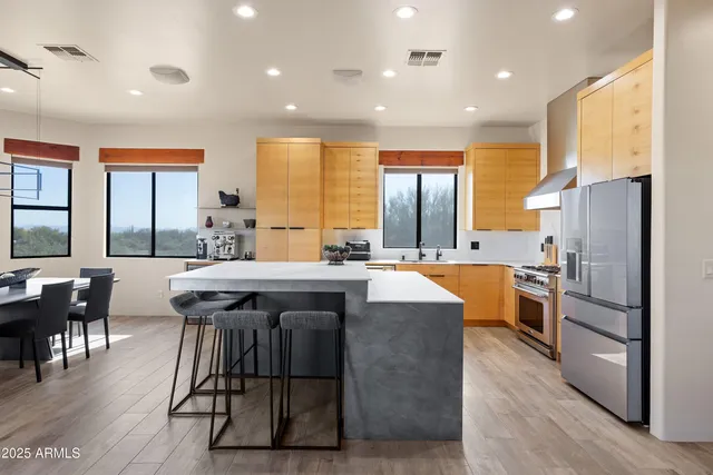 a kitchen with stainless steel appliances granite countertop a table chairs sink refrigerator and cabinets