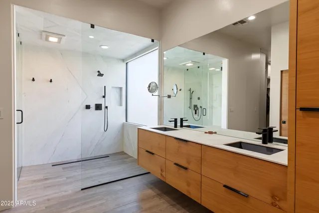 a bathroom with a double vanity sink a large mirror and shower