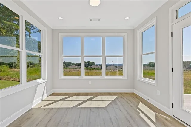 a view of an empty room with a window and wooden floor