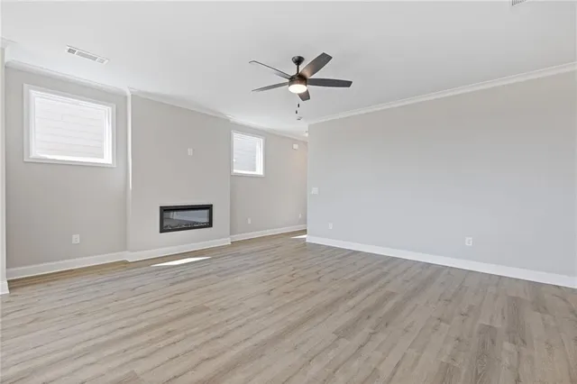 an empty room with wooden floor fan and windows