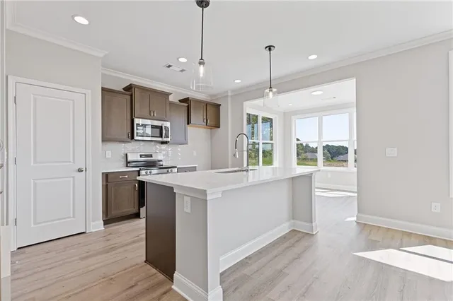 a kitchen with kitchen island a sink a stove a refrigerator and white cabinets