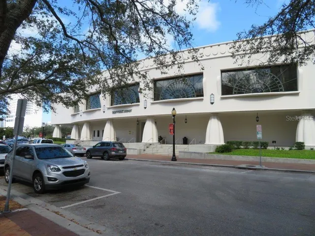 a view of road with card parked on side and retail shops