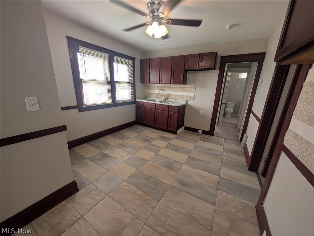 7515 Ottawa Road Cleveland, OH 44105 - Photo 6 of 21 Kitchen area featuring a ceiling fan with integrated lighting, wood-finish cabinetry, a stainless steel sink, a tiled backsplash, and patterned tile flooring
