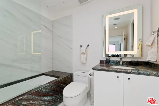 a bathroom with a granite countertop toilet sink and mirror