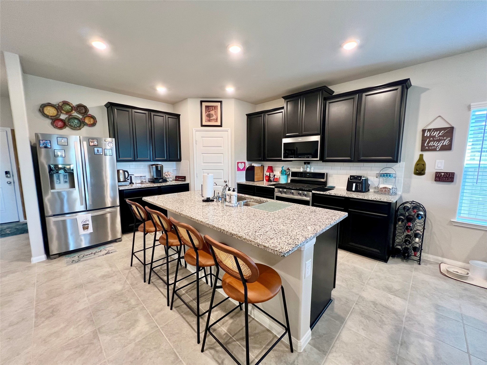 10013 Hermann Trace Texas City, TX 77591 - Photo 5 of 22 a kitchen with stainless steel appliances kitchen island granite countertop a refrigerator a sink a stove a microwave a dining table and chairs