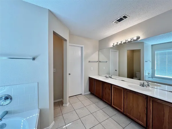 a bathroom with a double vanity sink mirror and bathtub