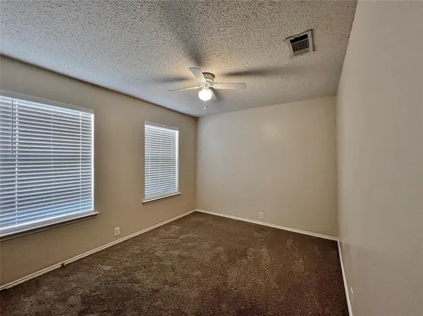 an empty room with windows and fan