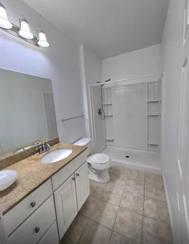 a bathroom with a granite countertop sink toilet and shower